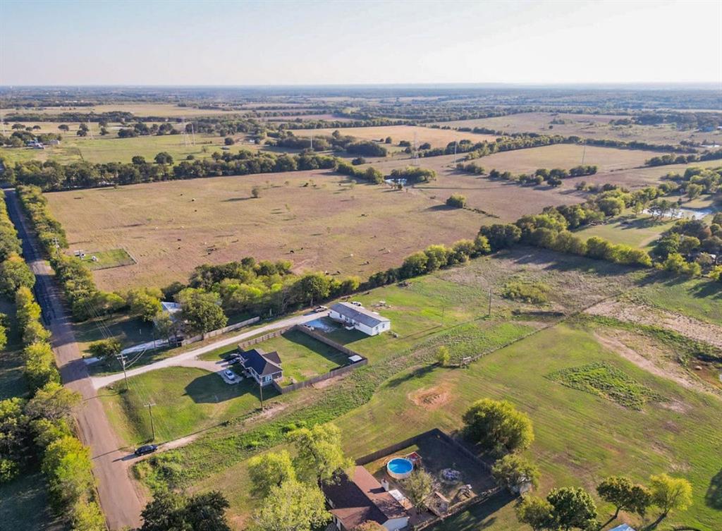 Aerial perspective featuring extensive acreage, mature trees, open pastureland, and established boundary fencing