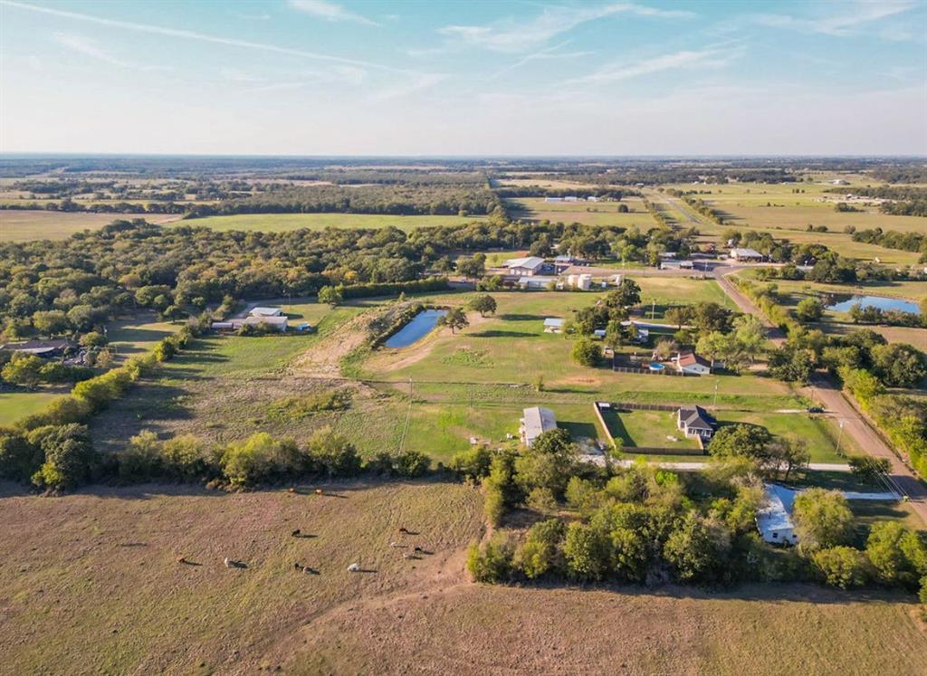 Expansive rural acreage featuring open pasture land, mature trees, and a private pond