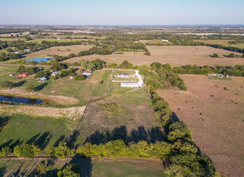 Aerial perspective of expansive acreage featuring fenced perimeter, open pastures, and mature treelines