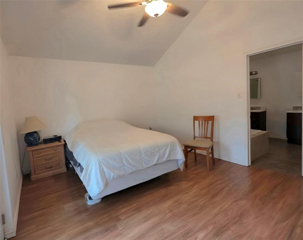 Room featuring vaulted ceiling, wood-finish flooring, and ceiling fan with integrated lighting