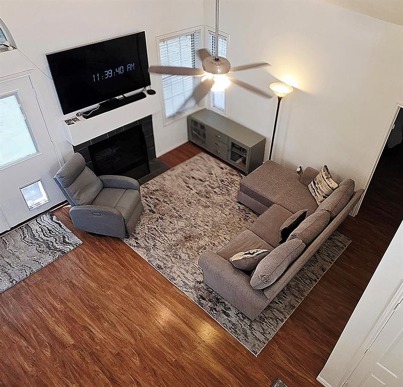 Vaulted ceilings, wood-finish flooring, and a stone-surround fireplace with a custom mantel