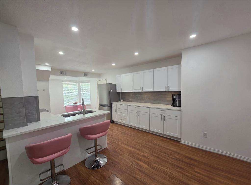 Kitchen Dining bar featuring white shaker-style cabinetry, quartz countertops, a peninsula with a stainless steel undermount sink, wood-finish flooring, and recessed ceiling lighting