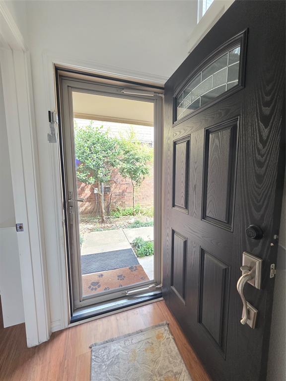 Entryway featuring a dark-toned wood-grain paneled front door with an arched glass inset, brushed nickel hardware, and full-length storm door with integrated screen