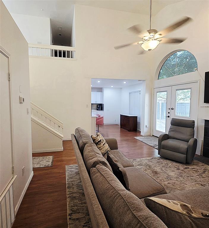 Vaulted ceilings, wood-finish flooring, an arched window, a built-in staircase with a railing, and a ceiling-mounted light fixture