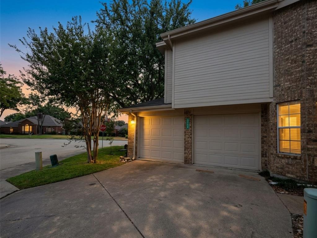 Exterior elevation featuring a two-car garage, brick veneer siding, horizontal lap siding, and a concrete driveway