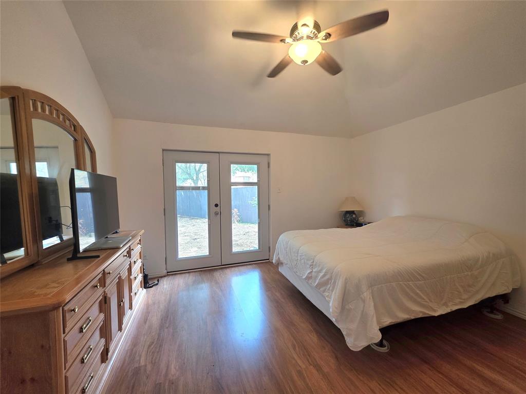 Vaulted ceiling with an integrated ceiling fan and wood-finish flooring featuring dual glass-paned doors
