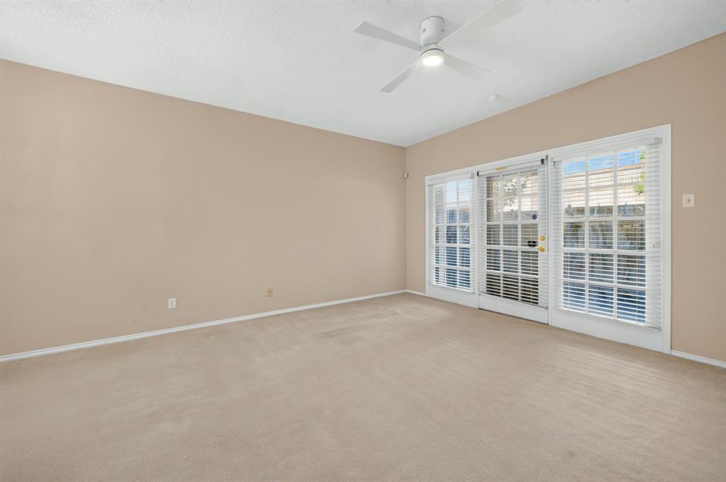Interior space featuring wall-to-wall carpeting, a ceiling fan with integrated lighting, and triple glass-paned doors with horizontal blinds