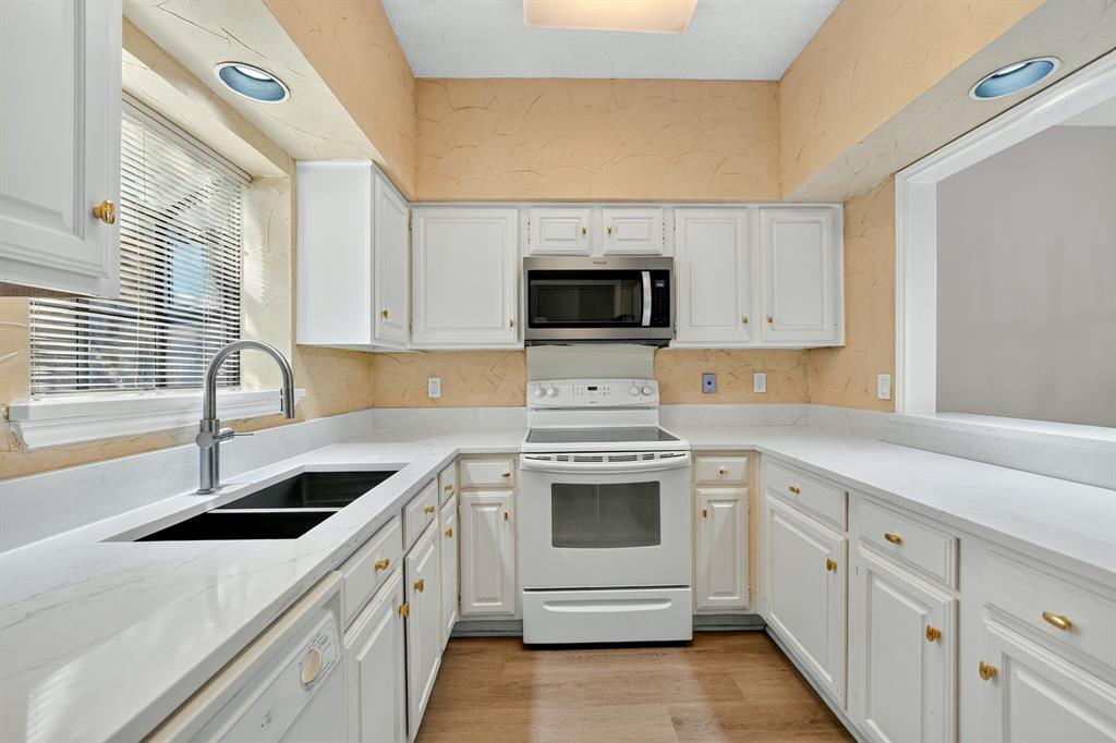 Bright, updated kitchen featuring brand-new granite countertops, fresh modern flooring, clean white cabinetry, and a pass-through breakfast bar.