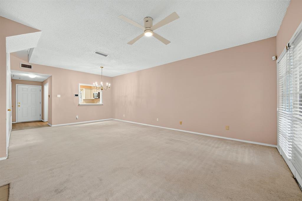 Expansive room featuring vaulted ceilings, a ceiling fan with integrated lighting, a pass-through opening, and sliding glass doors with window blinds