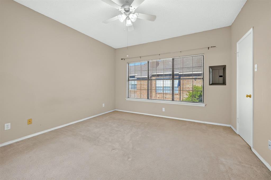 Neutral-toned interior featuring wall-to-wall carpeting, a multi-blade ceiling fan, and a large multi-pane window