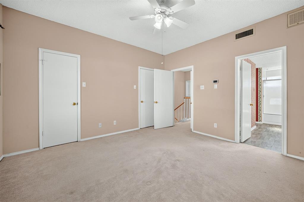 Neutral wall tones, wall-to-wall carpeting, and a ceiling-mounted fan with integrated light fixture