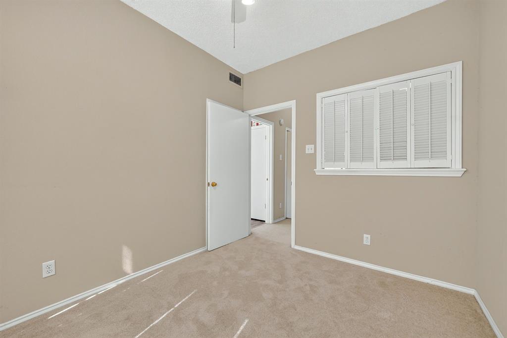 Neutral-toned interior space featuring wall-to-wall carpeting, white plantation shutters, and a ceiling-mounted light fixture