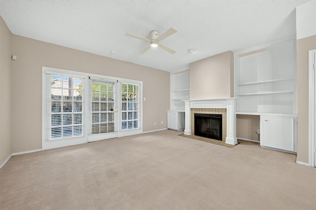 Fireplace with tile surround, built-in cabinetry with integrated shelving, triple-panel glass doors, and a ceiling-mounted fan