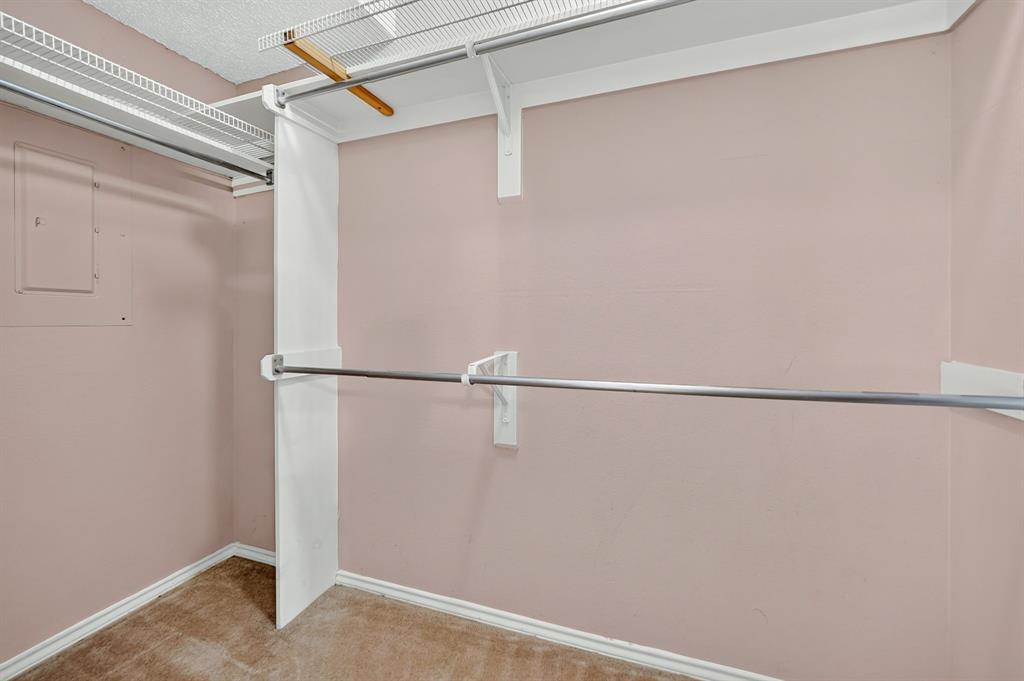 Walk-in closet featuring multi-level metal hanging rods, built-in wire shelving, and neutral wall-to-wall carpeting
