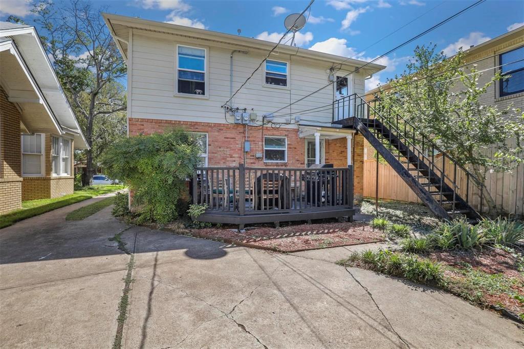 Exterior featuring brick and horizontal siding, a raised wood-finish deck with railings, and a metal staircase