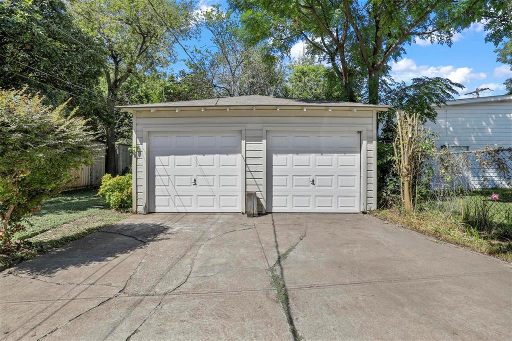 Detached two-car garage featuring horizontal siding, a low-pitched roof, and dual paneled overhead doors with a concrete driveway