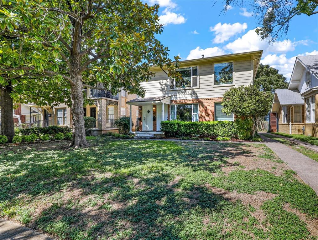 Two-story residence featuring a mixed-material exterior of horizontal siding and brick cladding, a covered entryway, and a concrete driveway