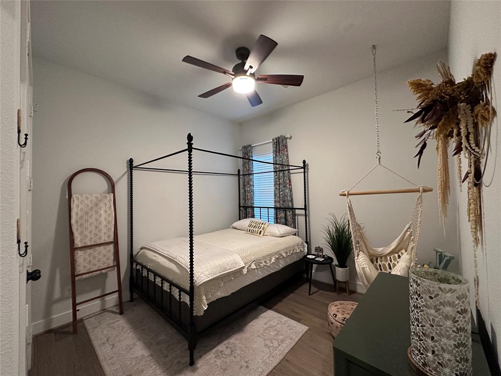 Room featuring wood-finish flooring, a ceiling fan with integrated lighting, and a window with neutral-toned hardware
