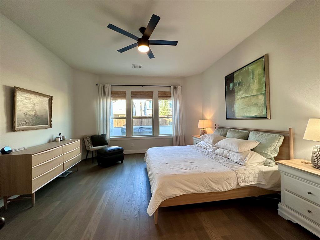 Spacious interior featuring wood-finish flooring, a matte black multi-blade ceiling fan, and three panel windows with integrated hardware
