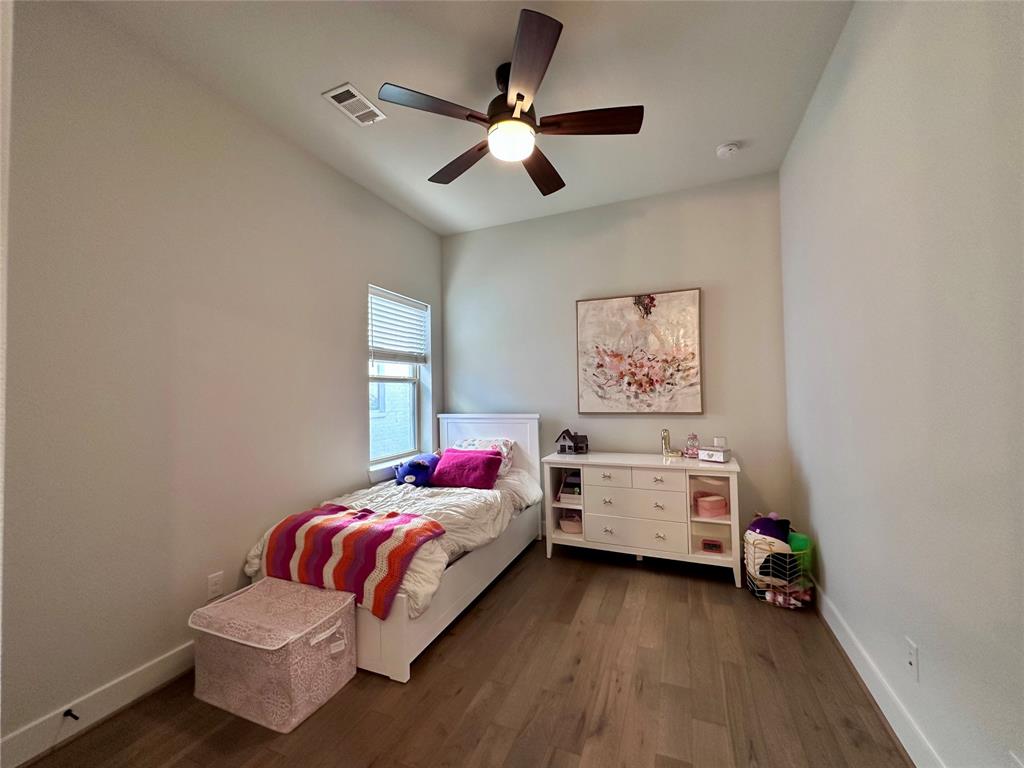 Room featuring high ceilings, wood-finish flooring, and a ceiling fan with integrated lighting