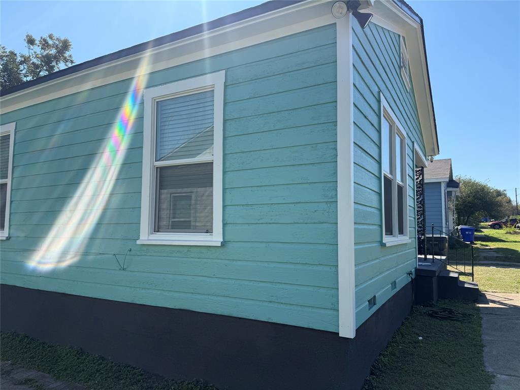 Exterior siding finished in a vibrant blue-green tone with contrasting white trim, horizontal lap cladding, and dual-pane windows