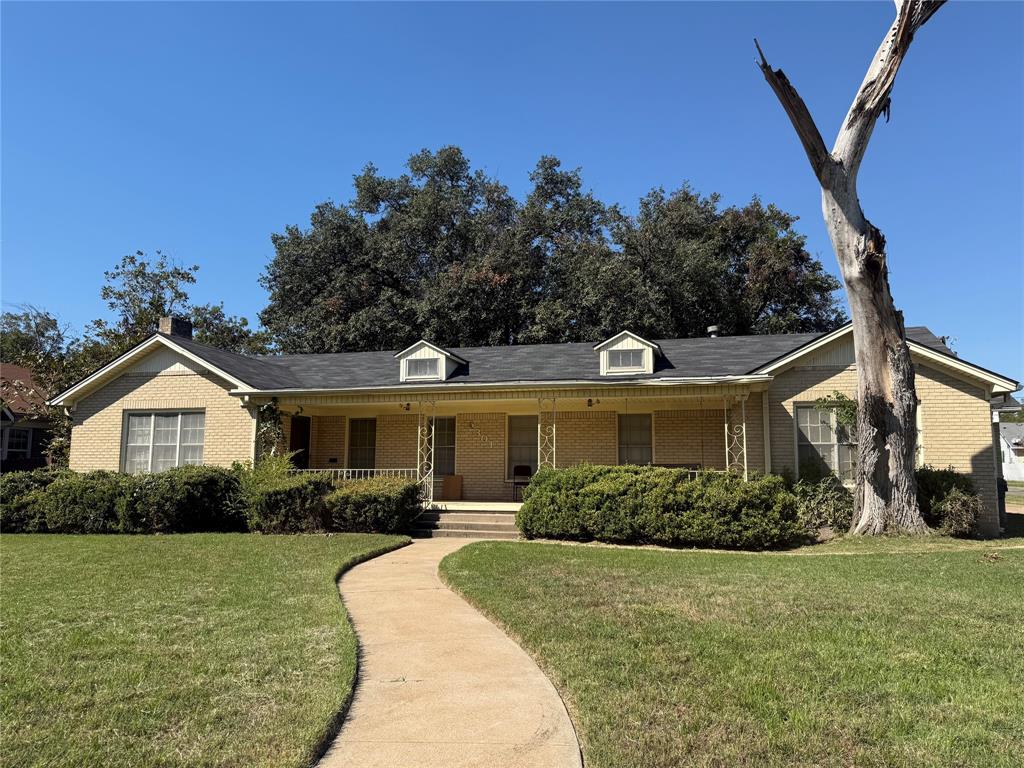 Single-story brick exterior featuring a covered front porch, dual dormers, and a paved walkway Single-story brick exterior featuring a covered front porch, dual dormers, and a paved walkway