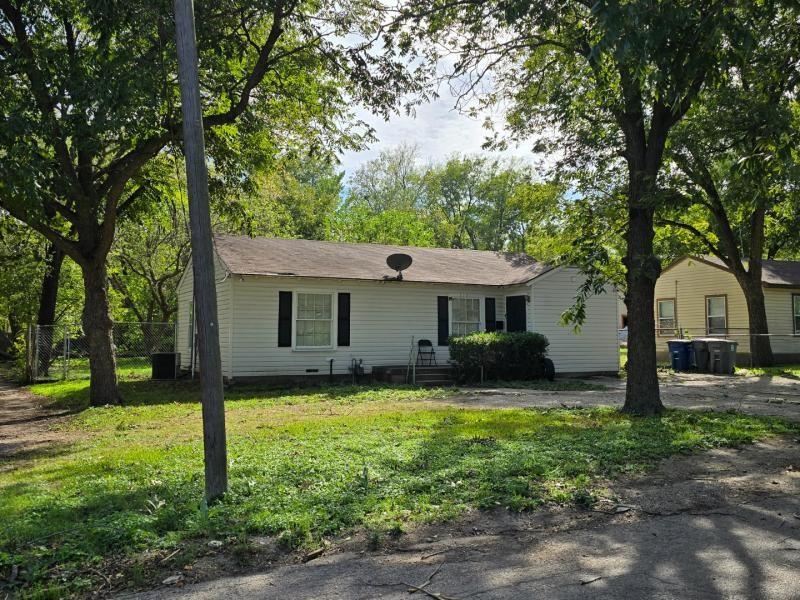 Single-story residence featuring horizontal lap siding, dark shutter accents, and mature trees on a level lot