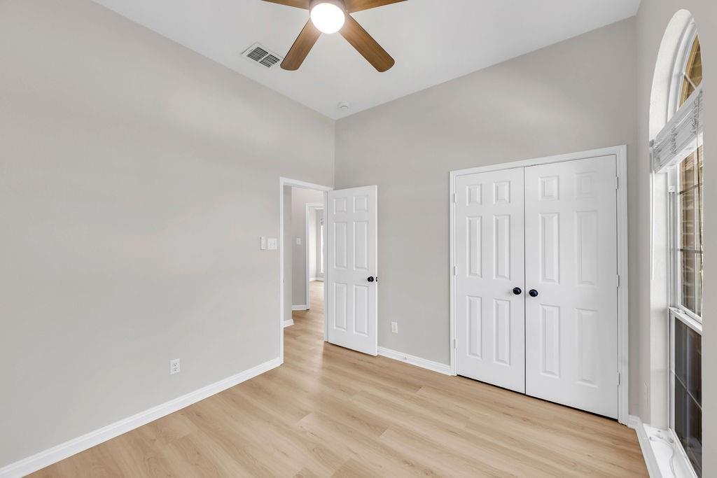 Interior space featuring high ceilings, wood-finish flooring, an arched window, and dual-panel closet doors with matte black hardware
