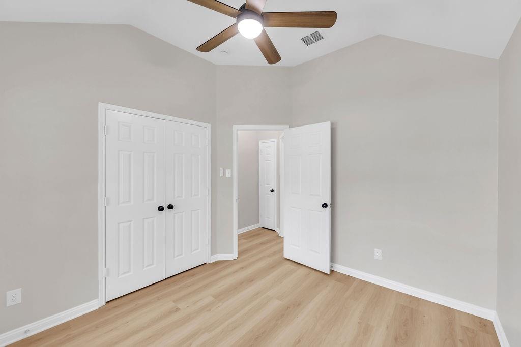 Vaulted ceilings, wood-finish flooring, and a ceiling fan with integrated lighting