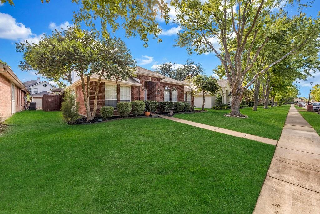 Brick exterior featuring arched window detailing, a recessed entryway, and mature landscaping