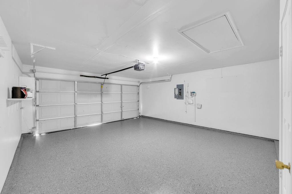 Finished garage featuring epoxy flooring, an automatic door opener, and ceiling access hatch