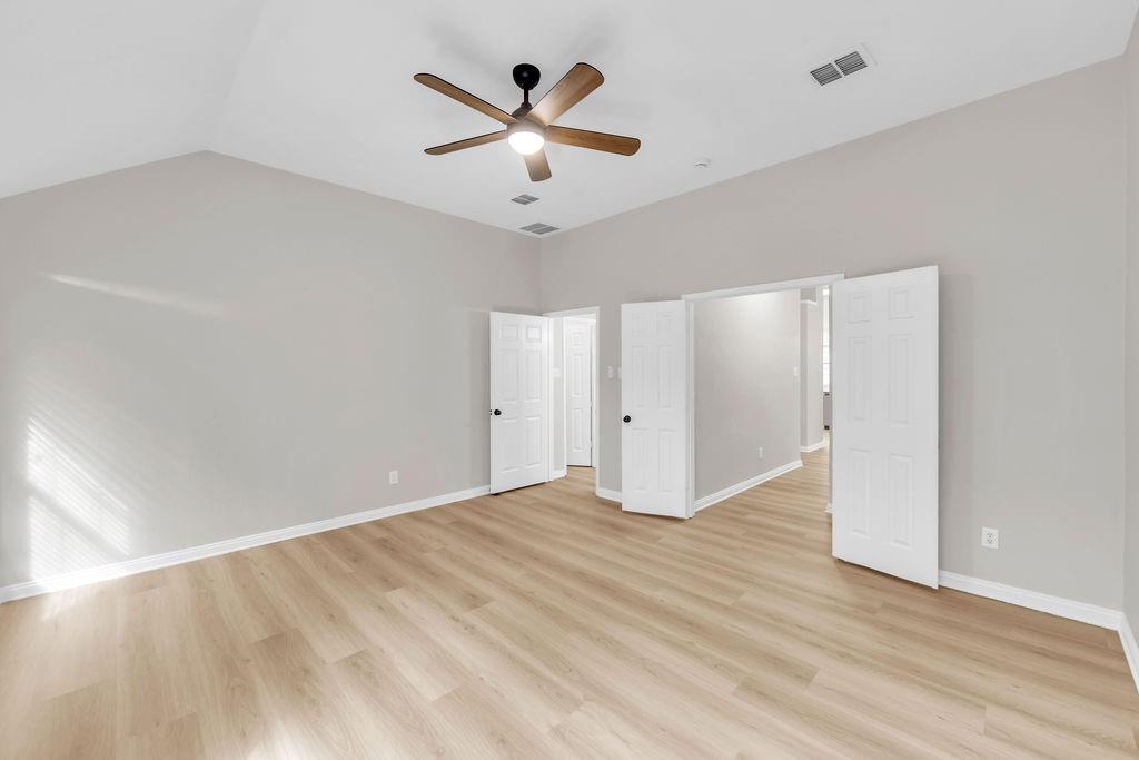 Vaulted ceilings, wood-finish flooring, and a central ceiling fan with integrated lighting