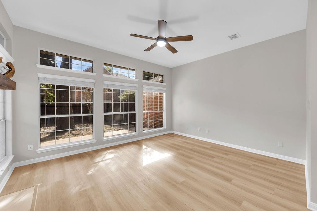 Living area featuring wood-finish flooring, high ceilings, large windows with transom panels, and a center ceiling fan