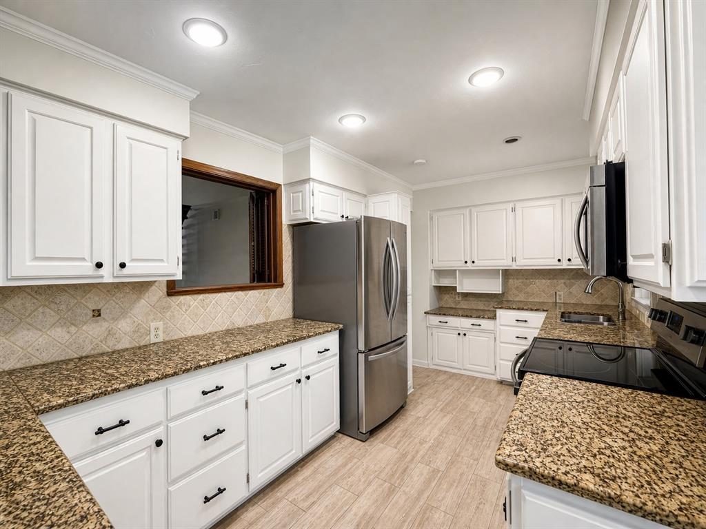 Kitchen featuring white cabinetry, stone-finish countertops, tile backsplash, stainless steel appliances, and wood-finish flooring