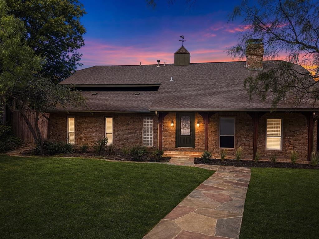 Brick exterior featuring a multi-gabled roofline, a decorative cupola with a weathervane, natural stone walkway, and a covered front porch with timber support posts