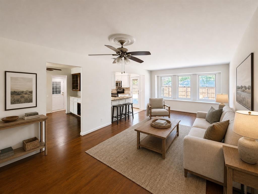 Living area featuring wood-finish flooring, a ceiling fan with decorative medallion, and multiple windows