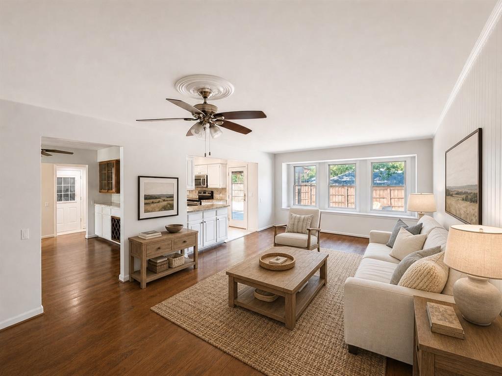 Living area featuring wood-finish flooring, a ceiling fan with decorative medallion, beadboard wall detailing, and a triple window configuration