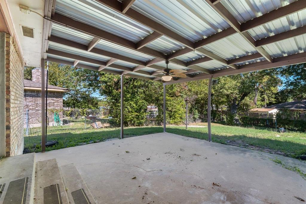 Covered concrete patio featuring a structural metal frame, overhead ceiling fan with light fixture, brick exterior wall, and tiered concrete steps