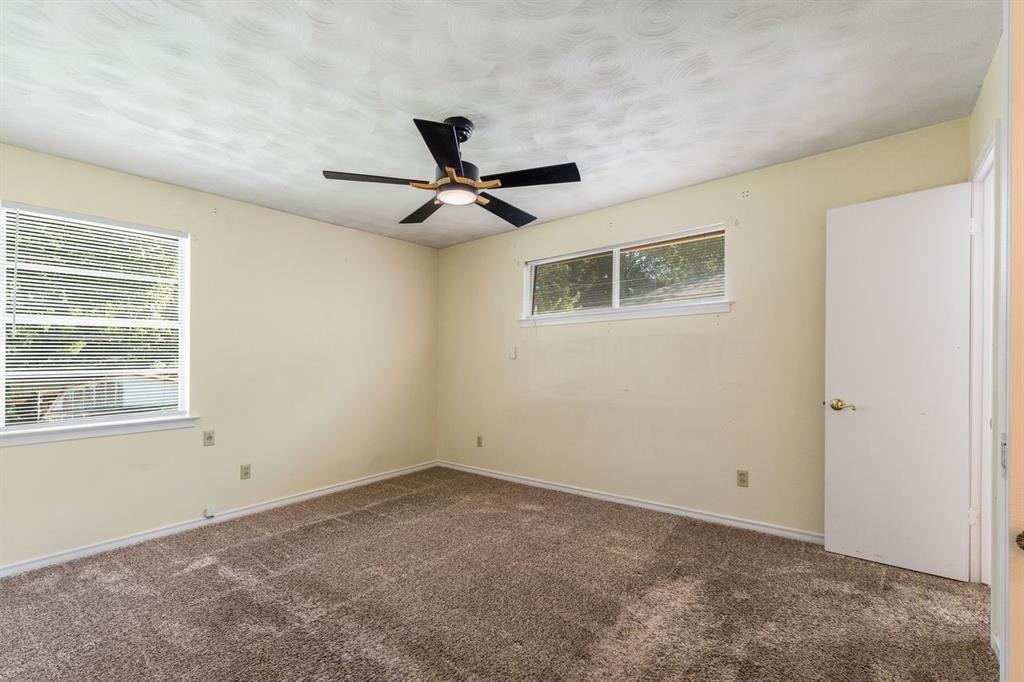 Room featuring neutral wall tones, carpeted flooring, a ceiling fan with integrated lighting, dual windows, and a solid interior door