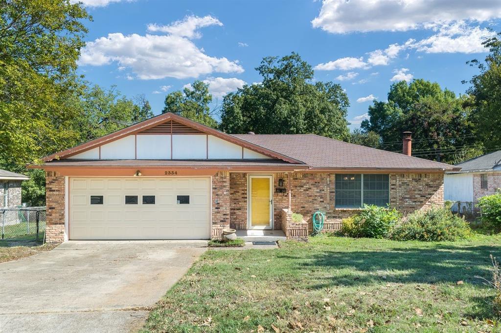 Single-story residence featuring a brick exterior, attached two-car garage, gable roofline, and front lawn