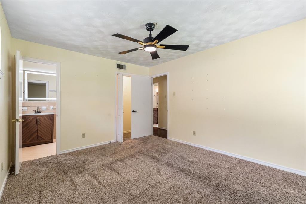 Interior room featuring neutral carpeting, a central ceiling fan with integrated lighting, and multiple points of entry
