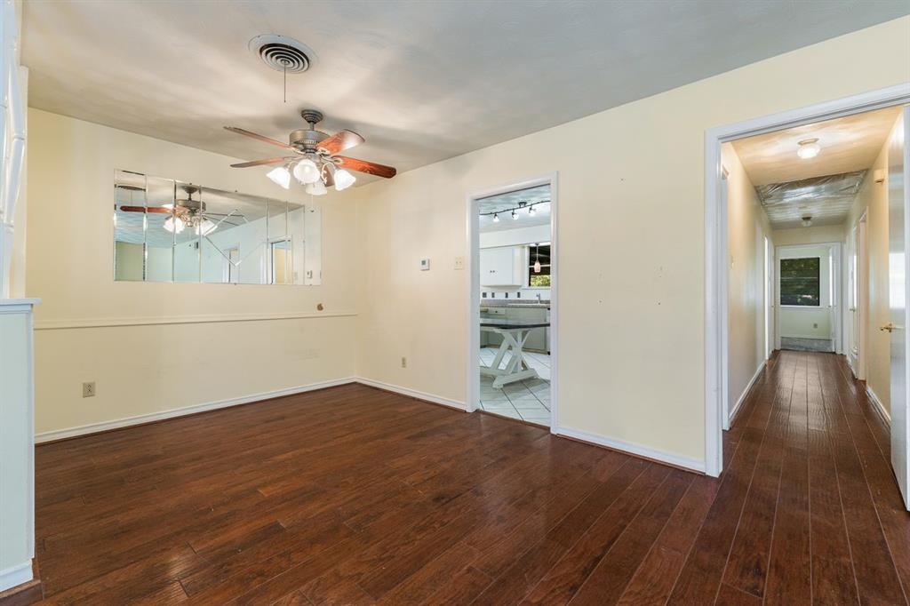 Interior space featuring dark wood-finish flooring, a wall-mounted multi-panel mirror, and a ceiling-mounted light fixture with a fan