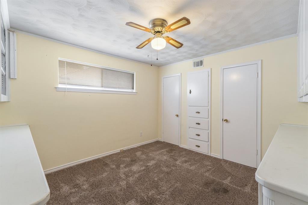 Room featuring a ceiling fan with integrated lighting, neutral wall-to-wall carpeting, and a built-in cabinet with integrated drawers