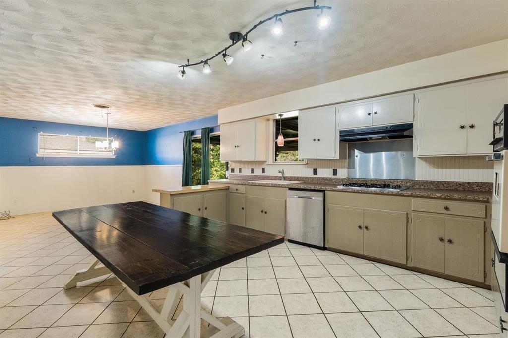 Kitchen featuring tile flooring, metal backsplash, built-in dishwasher, and adjustable track lighting