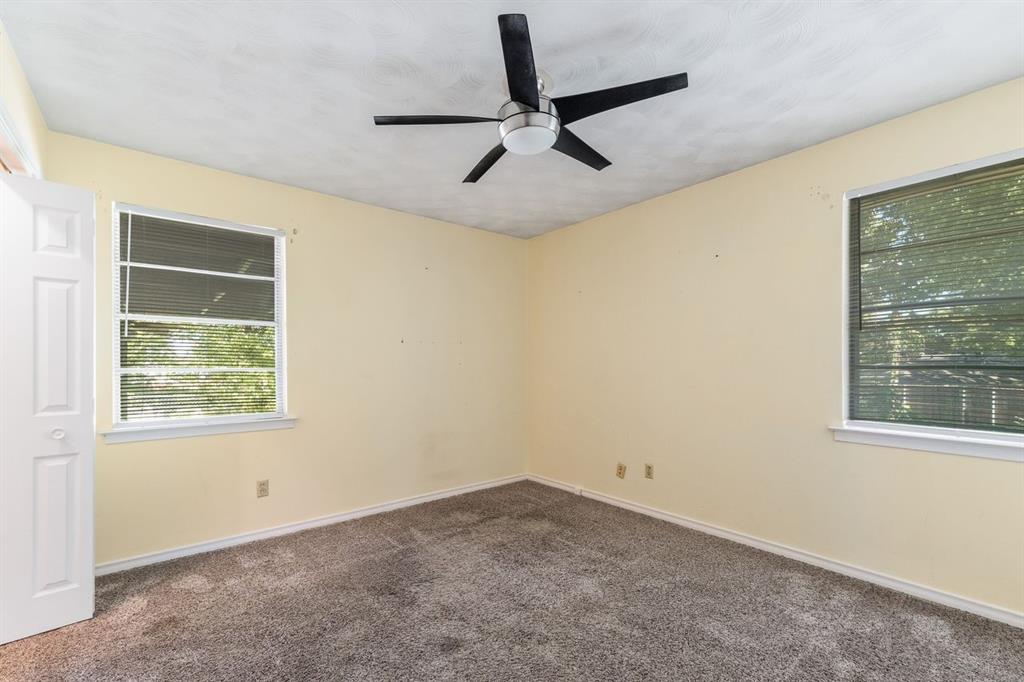 Interior room featuring neutral wall paint, wall-to-wall carpeting, two dual-pane windows, and a ceiling-mounted fan with integrated lighting