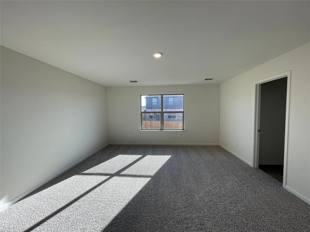 Neutral-toned interior space featuring neutral carpeting, a central recessed light fixture, and a single-pane window with a sill