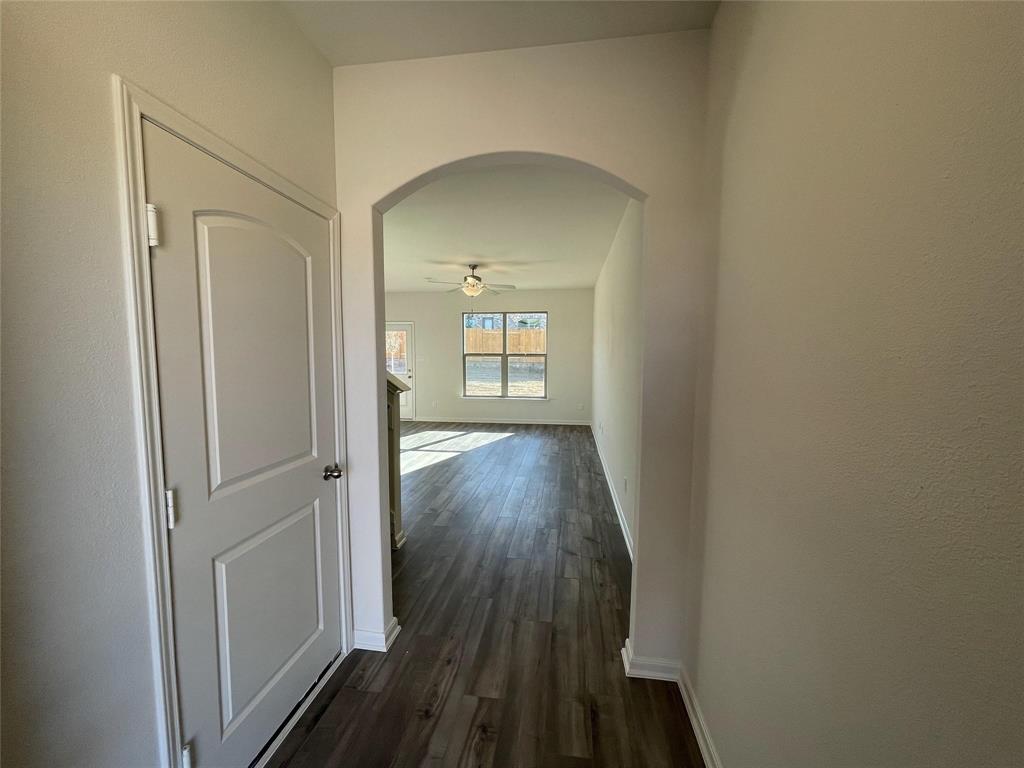 Interior entryway featuring an arched passage, wood-finish flooring, and a two-panel interior door with brushed nickel hardware Interior entryway featuring an arched passage, wood-finish flooring, and a two-panel interior door with brushed nickel hardware