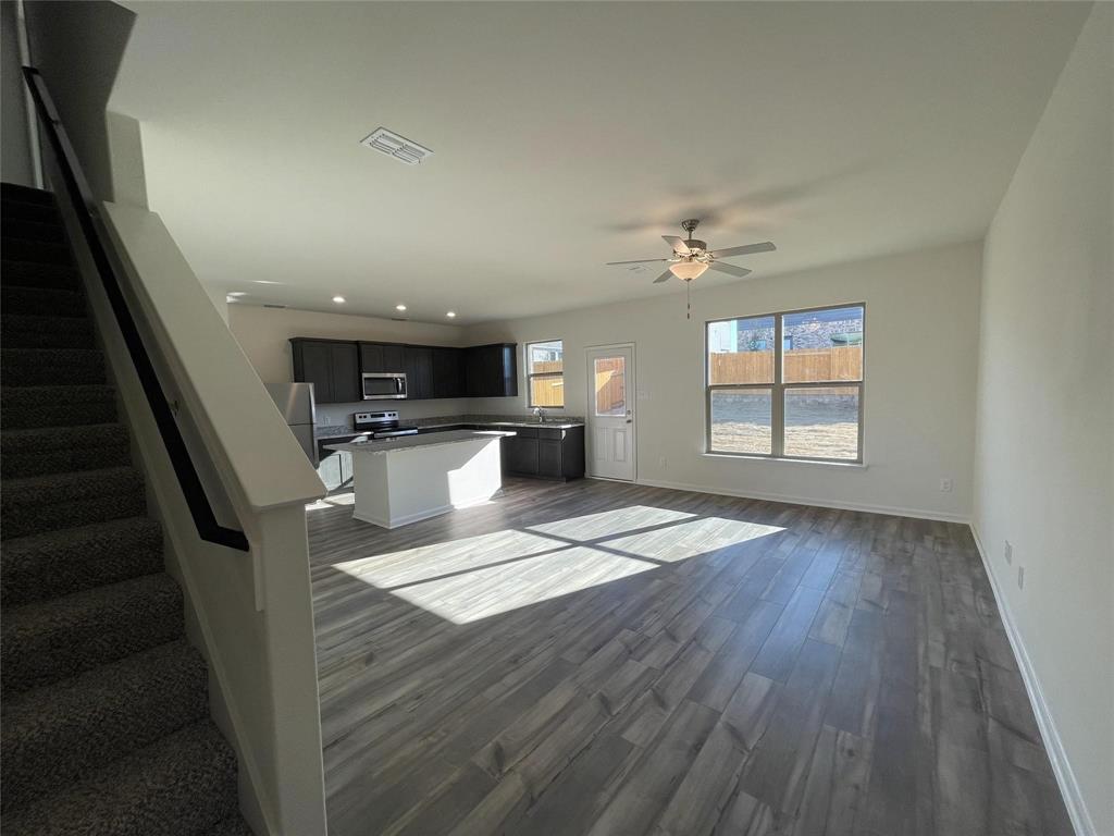 Open floor plan featuring wood-finish flooring, a kitchen island, dark cabinetry, and a ceiling fan