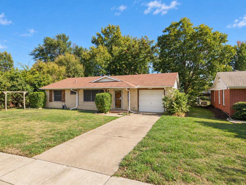 Single-story brick exterior featuring a multi-gable roofline, attached one-car garage, concrete driveway, and front lawn Single-story brick exterior featuring a multi-gable roofline, attached one-car garage, concrete driveway, and front lawn