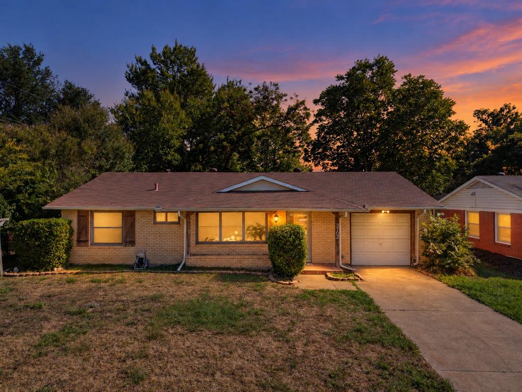 Single-story brick residence featuring a shingled roof, attached one-car garage, concrete driveway, and window shutters Single-story brick residence featuring a shingled roof, attached one-car garage, concrete driveway, and window shutters